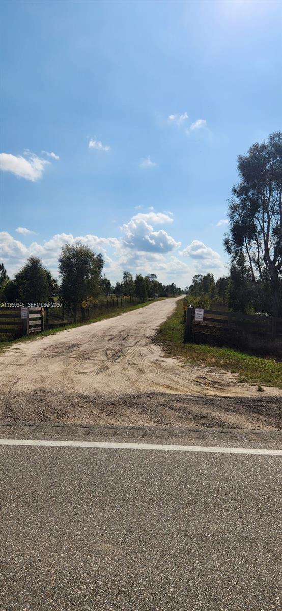 A dirt road leads through a gated entrance into a rural, wooded landscape — 48345 Bermont Rd, Punta Gorda FL 33982, PUNTA GORDA, FL