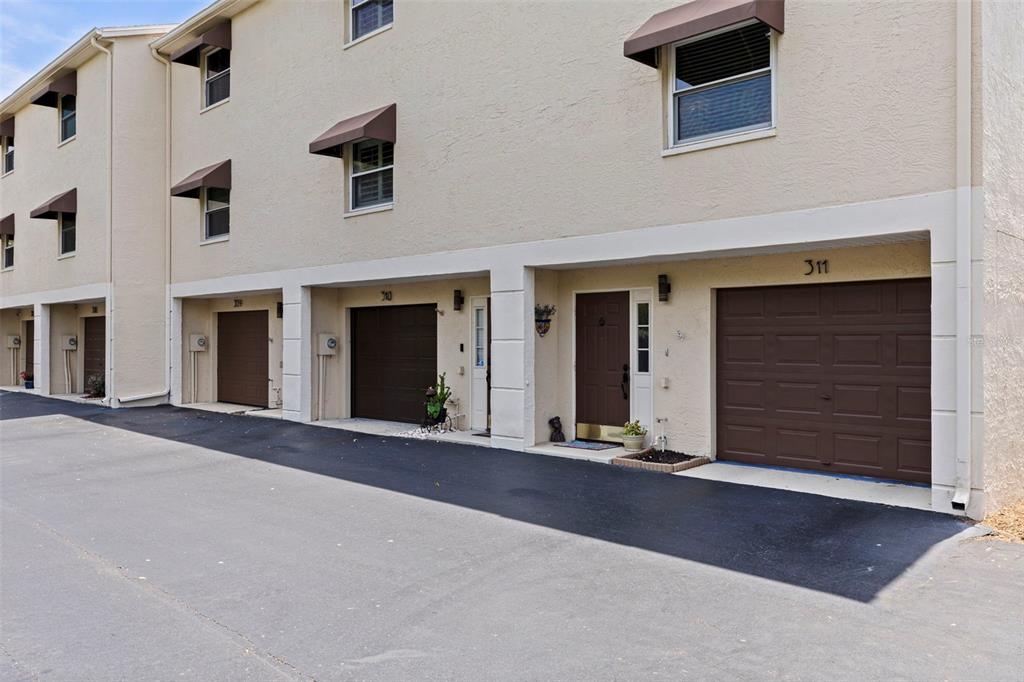 A row of townhouses features brown garage doors, tan stucco walls, and small awnings — 465 PINELLAS BAYWAY S UNIT 311, TIERRA VERDE, FL