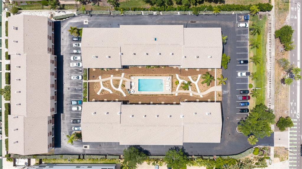An aerial view shows an apartment complex with a central courtyard, swimming pool, and parking — 465 PINELLAS BAYWAY S UNIT 311, TIERRA VERDE, FL