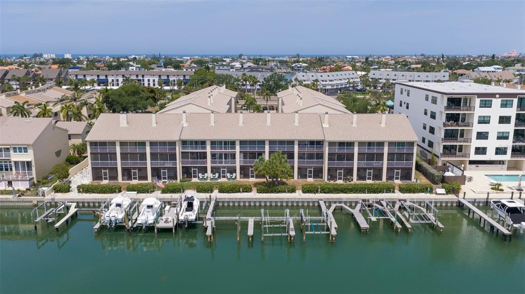 An aerial view shows a multi-story waterfront condominium building with private boat slips and docks — 465 PINELLAS BAYWAY S UNIT 311, TIERRA VERDE, FL