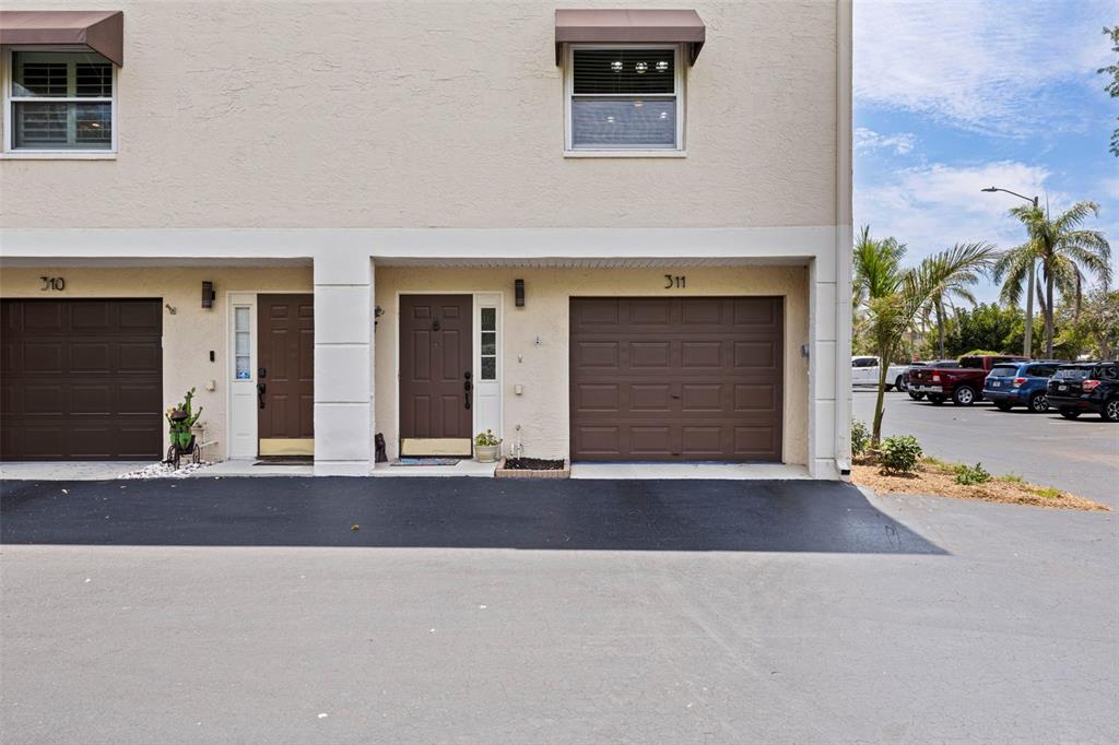 The exterior view shows two adjacent townhome units with brown garage doors and front entryways — 465 PINELLAS BAYWAY S UNIT 311, TIERRA VERDE, FL