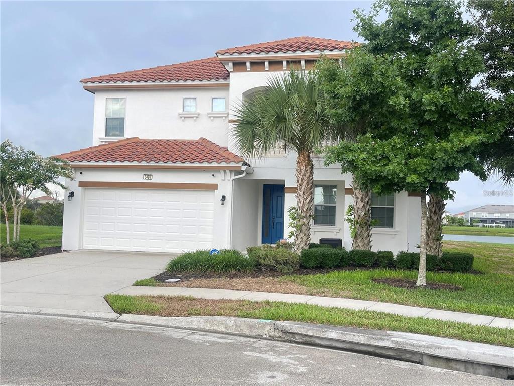 A two-story house with a white stucco exterior, red tile roof, and a blue front door — 5426 OAKGRAIN COURT, DAVENPORT, FL