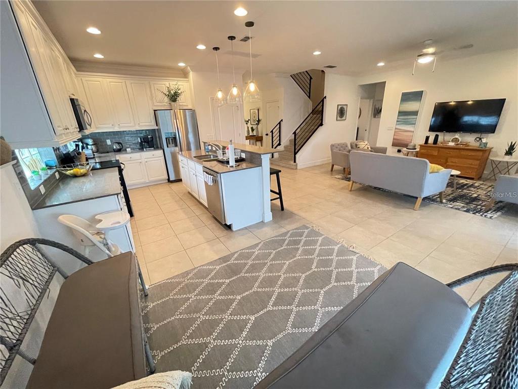 An open-concept kitchen and living area features white cabinetry, a central island, and tile flooring — 5426 OAKGRAIN COURT, DAVENPORT, FL