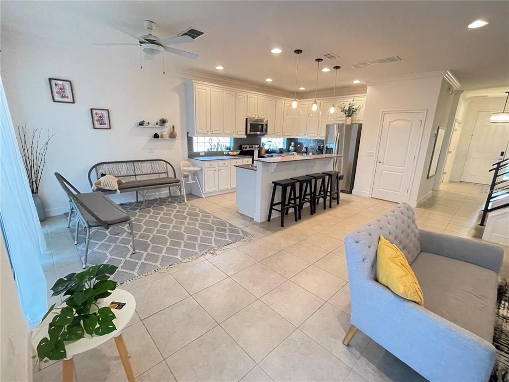 An open-concept kitchen and living area features white cabinetry, a breakfast bar, and tile flooring — 5426 OAKGRAIN COURT, DAVENPORT, FL