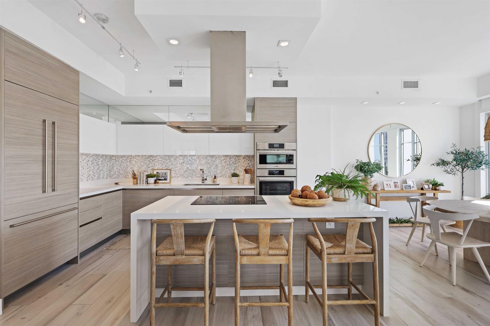A modern kitchen features light wood cabinetry, a white island with barstools, and stainless appliances — 155 E Boca Raton Road # 601, Boca Raton FL 33432, BOCA RATON, FL
