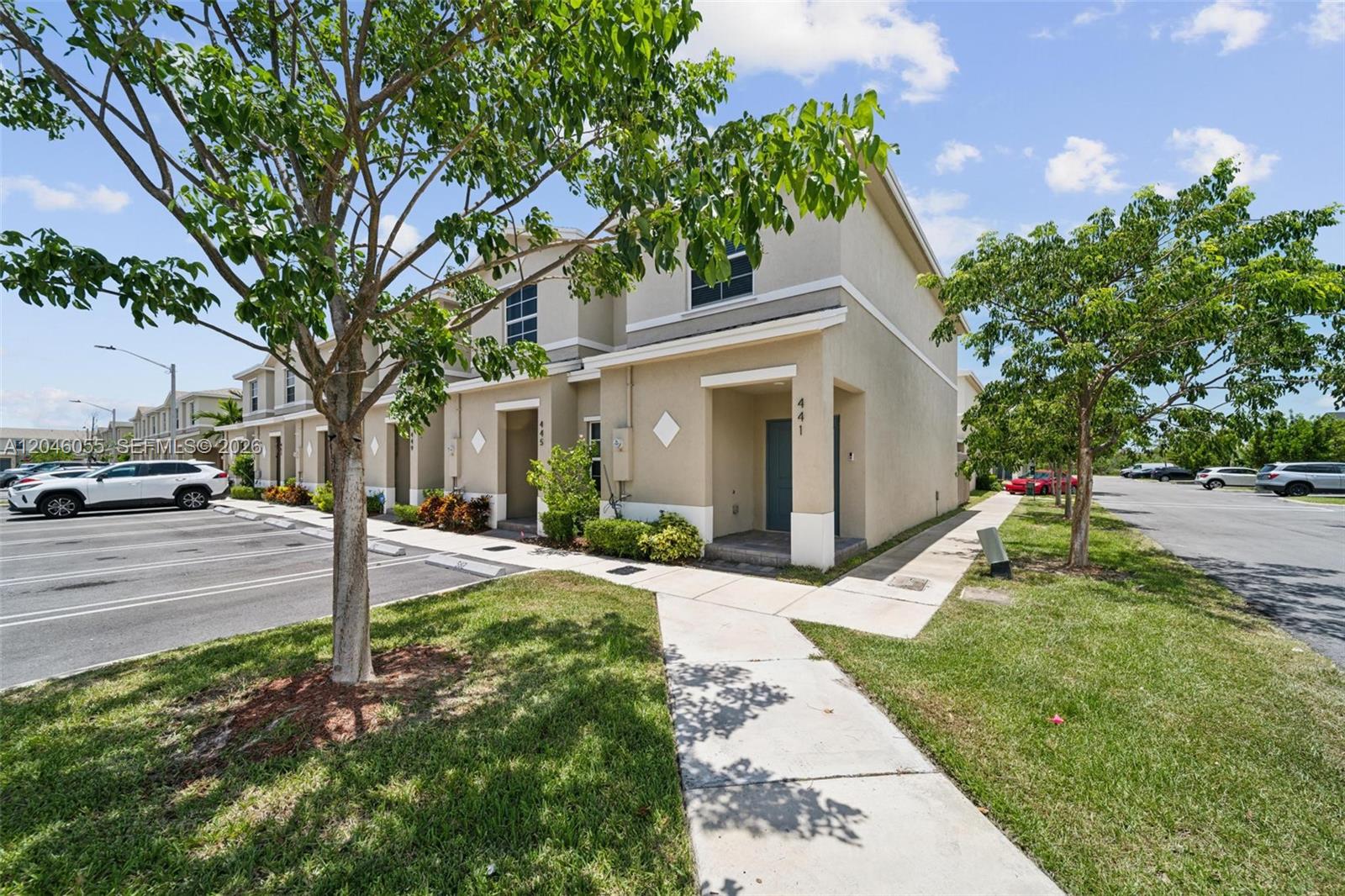 A two-story tan townhouse with a concrete walkway and parking spaces in front — 441 NE 4th Ln, Florida City FL 33034, FLORIDA CITY, FL
