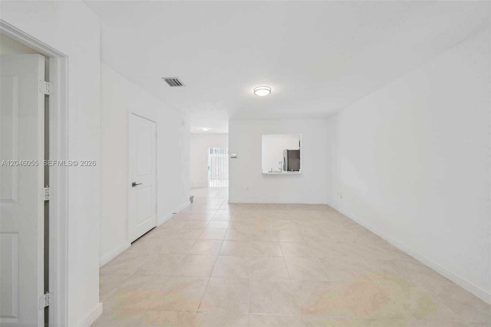 An empty room with white walls, tile flooring, a pass-through window, and a closed door — 441 NE 4th Ln, Florida City FL 33034, FLORIDA CITY, FL