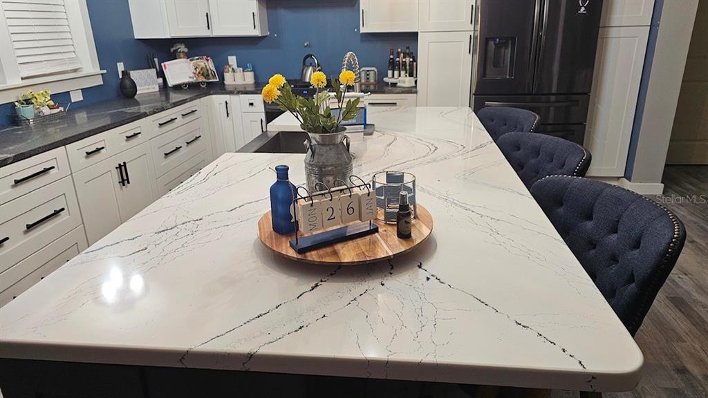 A kitchen island with a white marble-look countertop sits in front of blue kitchen cabinets — 42349 FONSECA LANE, DELAND, FL