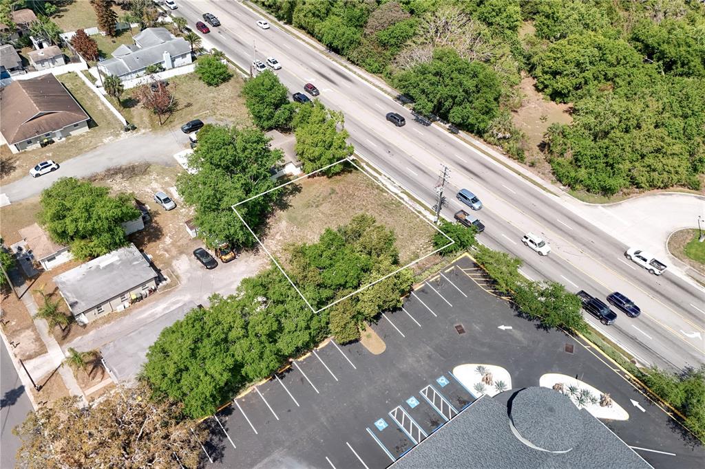 An aerial view shows a vacant, rectangular lot bordered by a road and a parking lot — W HWY 50, CLERMONT, FL