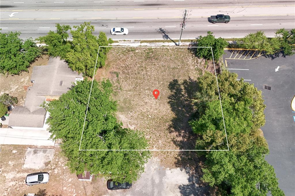 An aerial view shows a vacant, rectangular lot outlined in white next to a road — W HWY 50, CLERMONT, FL