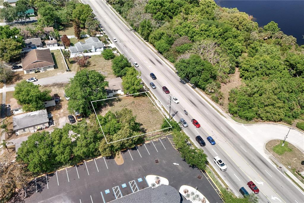 An aerial view shows a vacant, rectangular lot bordered by a road and parking lot — W HWY 50, CLERMONT, FL
