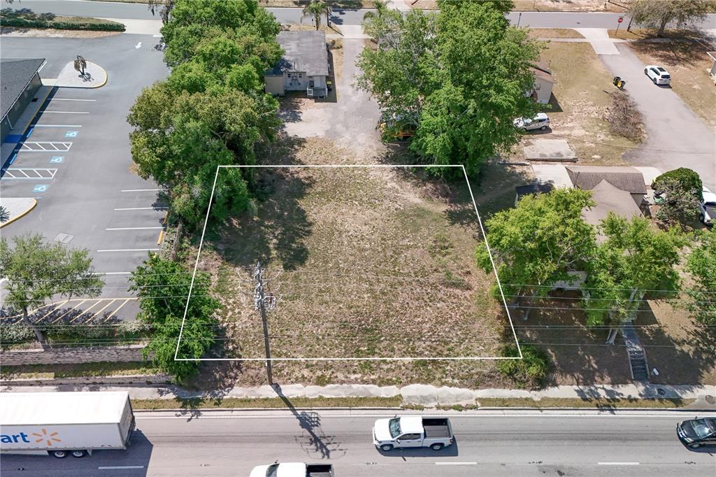 An aerial view shows a vacant, rectangular lot bordered by trees, a parking lot, and road — W HWY 50, CLERMONT, FL