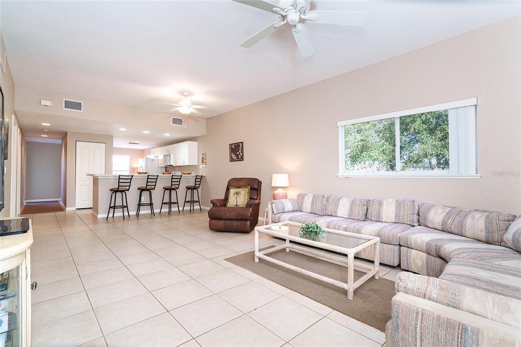 A living room with tile floors, a sectional sofa, and an open kitchen with bar seating — 8101 MEMORY LANE UNIT 122, ROTONDA WEST, FL