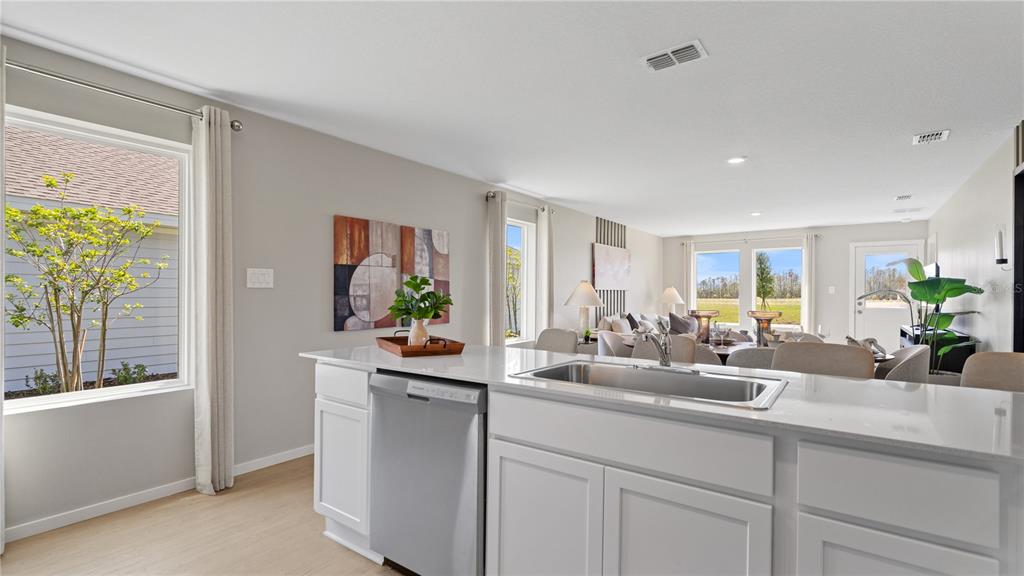 A kitchen island with a stainless steel dishwasher and sink overlooks an open-concept living area — 611 CHANNEL WAY, GROVELAND, FL