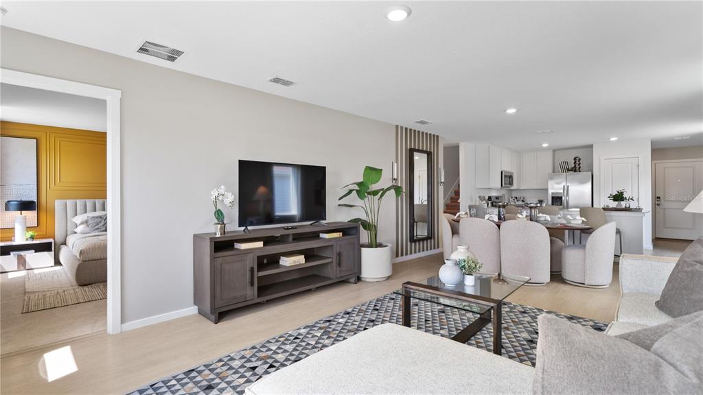 A living room with a television console, a patterned rug, and an open kitchen area — 611 CHANNEL WAY, GROVELAND, FL