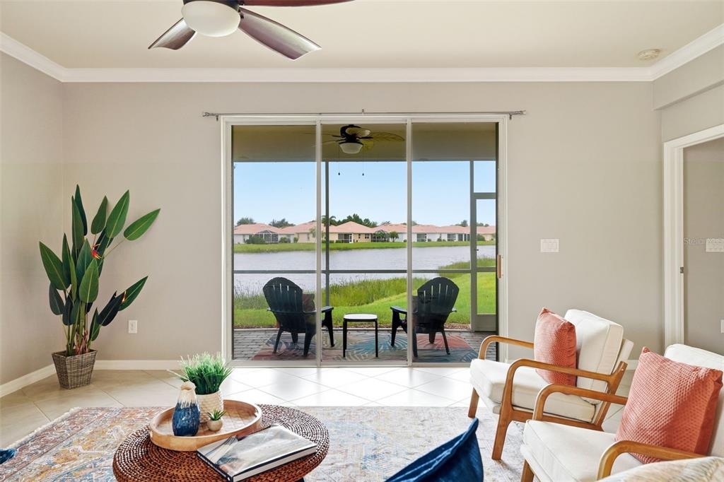 A living room features tile floors, a ceiling fan, and sliding doors overlooking a lake — 4993 BRITTAIN WAY, NORTH PORT, FL