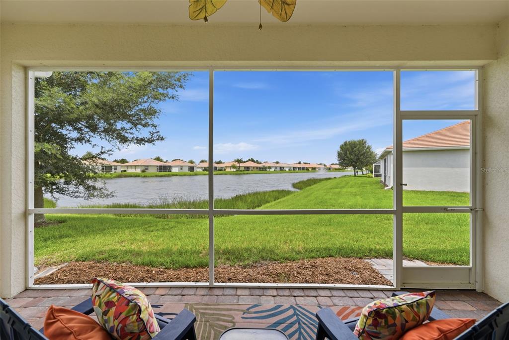 A screened-in patio overlooks a lake and a residential neighborhood on a sunny day — 4993 BRITTAIN WAY, NORTH PORT, FL