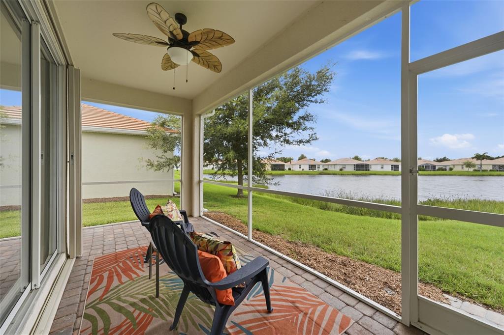 A screened-in patio with two chairs overlooks a grassy lawn and a lake — 4993 BRITTAIN WAY, NORTH PORT, FL