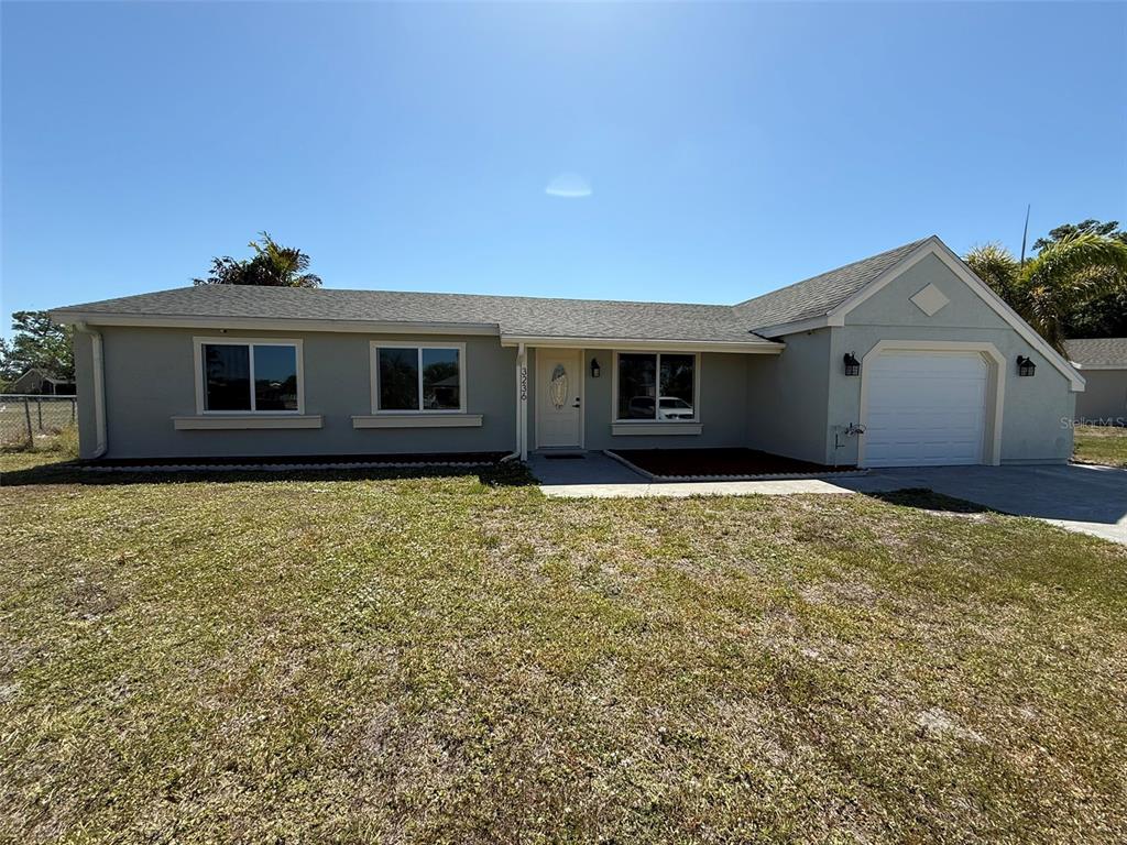 A single-story house with a light-colored exterior, a front-facing garage, and a grassy yard — 3236 MONTCLAIR CIRCLE, NORTH PORT, FL