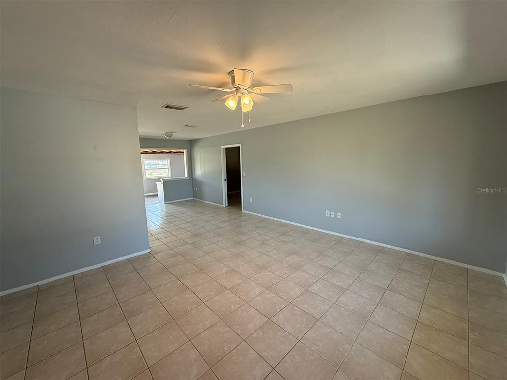 A spacious room with light gray walls, beige tile flooring, and a ceiling fan — 3236 MONTCLAIR CIRCLE, NORTH PORT, FL