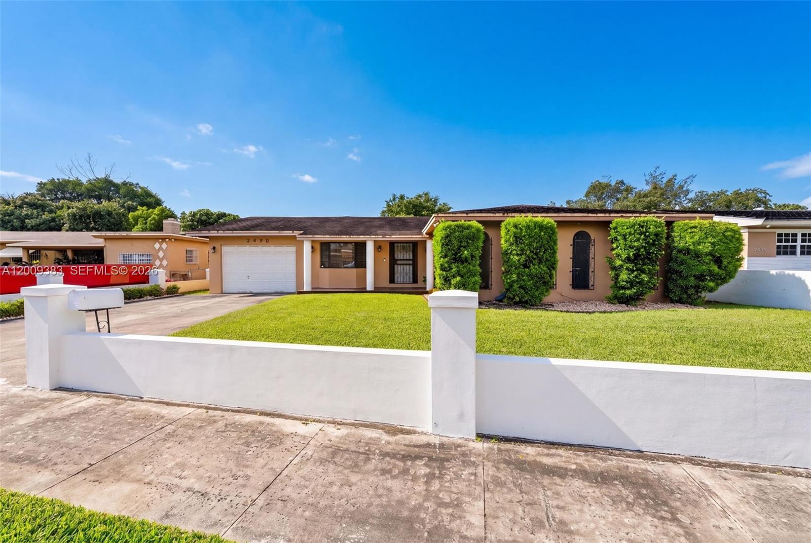 A single-story house with a tan exterior, a white garage door, and a front lawn — 2450 NW 108th St, Miami FL 33167, MIAMI, FL