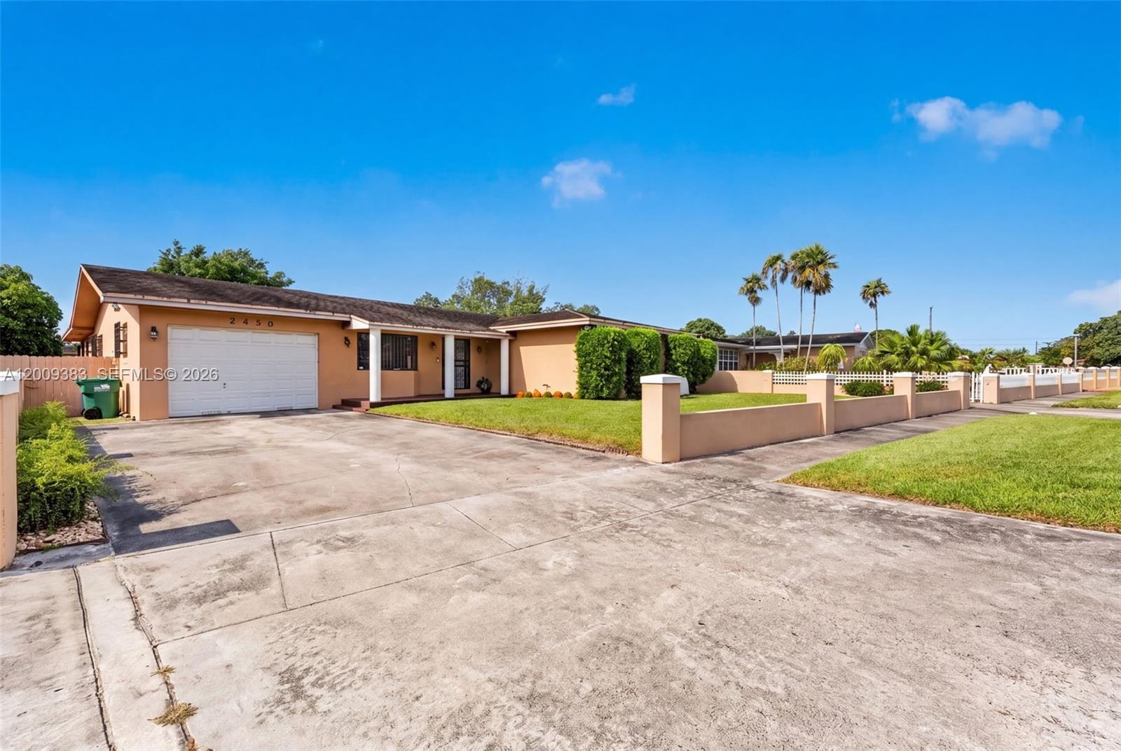 A single-story house with a concrete driveway, a two-car garage, and a low perimeter wall — 2450 NW 108th St, Miami FL 33167, MIAMI, FL