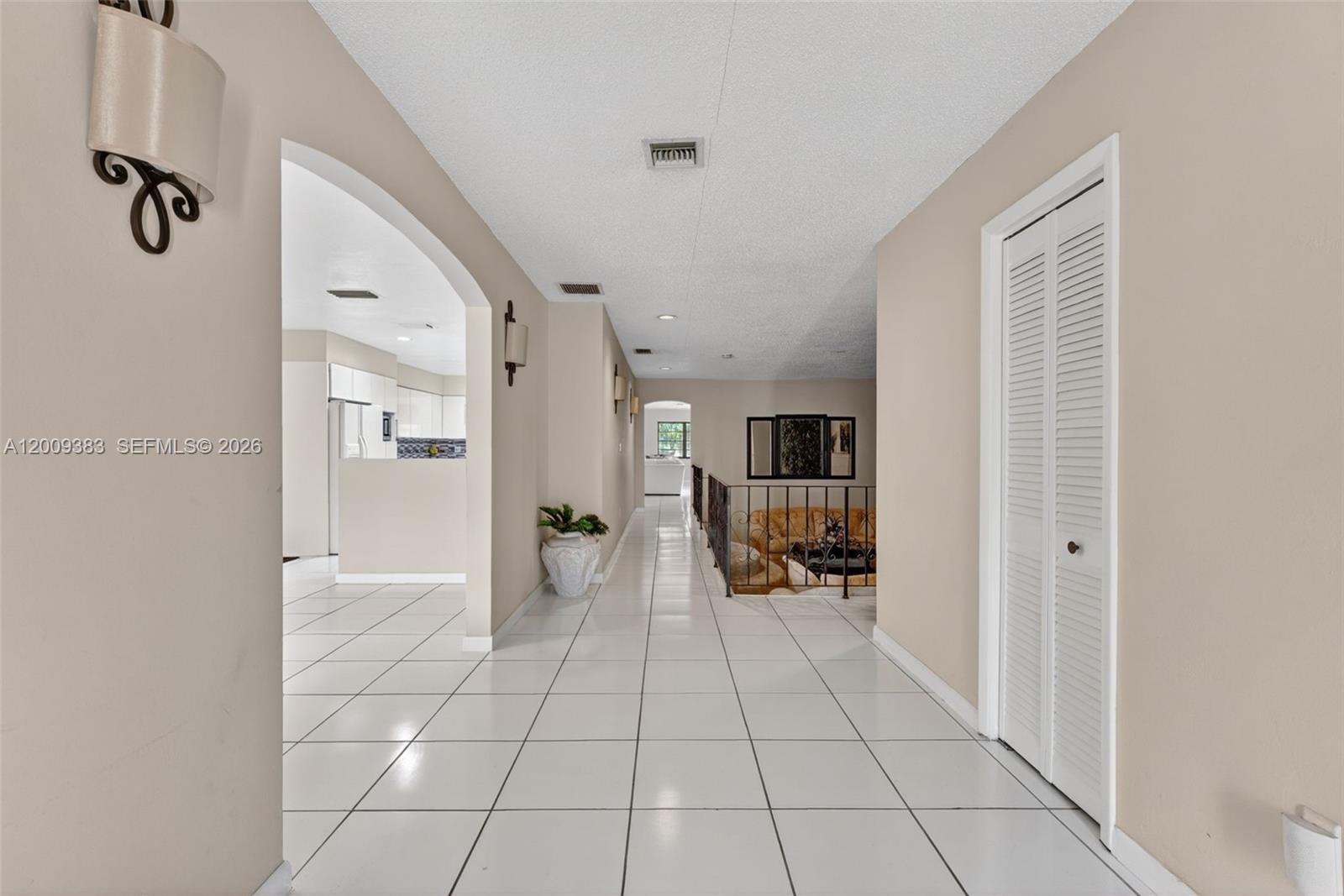 A tiled hallway leads to a sunken living area with an iron railing — 2450 NW 108th St, Miami FL 33167, MIAMI, FL