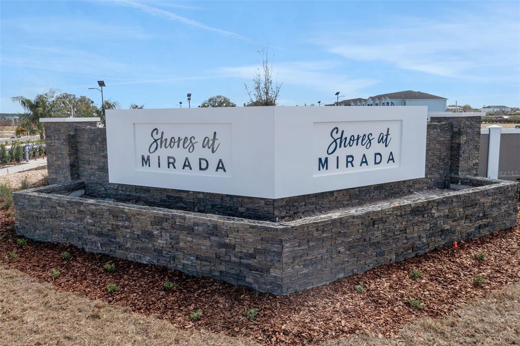 A stone-clad monument sign displays the name Shores at Mirada against a blue sky — 31825 KESTREL CALLING DRIVE, SAN ANTONIO, FL
