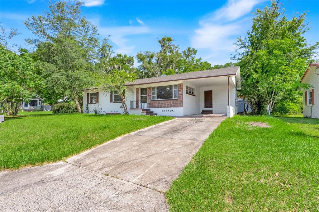 A single-story house with a white exterior, brick accents, and a concrete driveway — 439 W WISCONSIN AVENUE, DELAND, FL