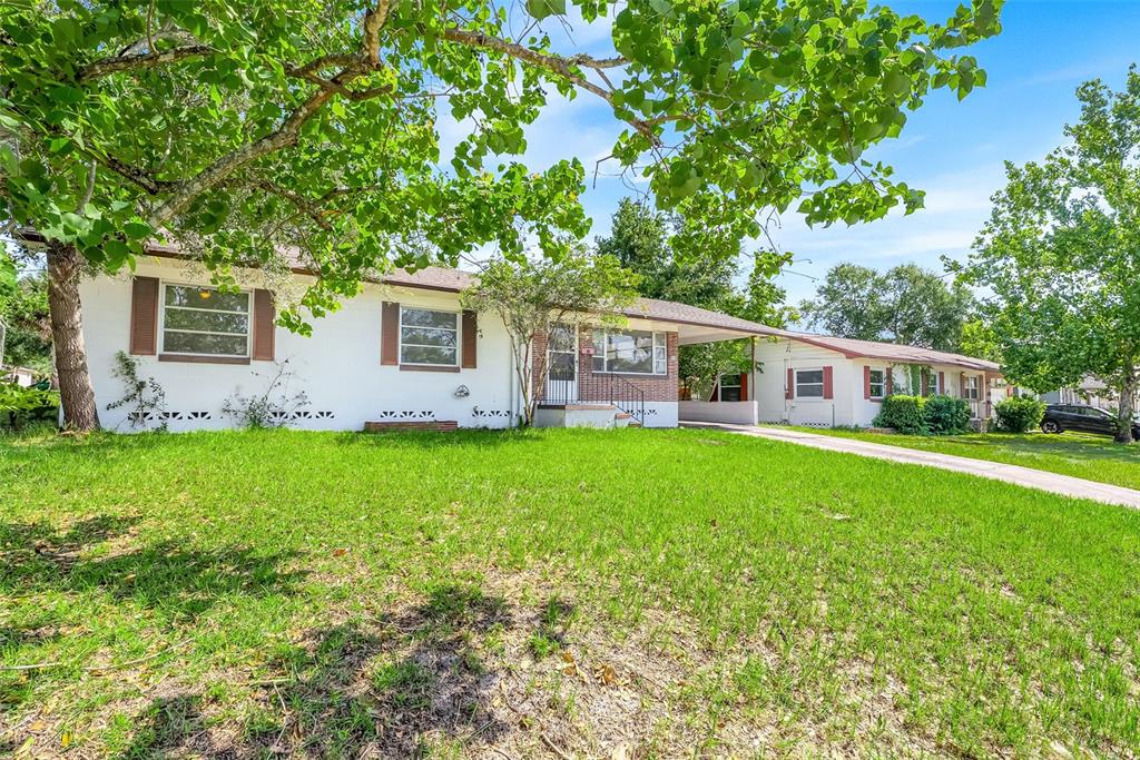 A white single-story house with brown shutters, a brick accent wall, and a carport — 439 W WISCONSIN AVENUE, DELAND, FL