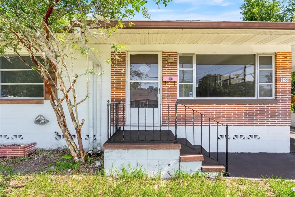The exterior of a house features a brick facade, a front porch, and a tree — 439 W WISCONSIN AVENUE, DELAND, FL