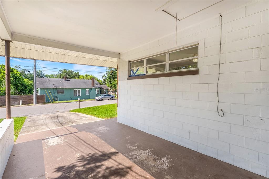 A covered concrete carport features a white painted block wall and a horizontal window — 439 W WISCONSIN AVENUE, DELAND, FL