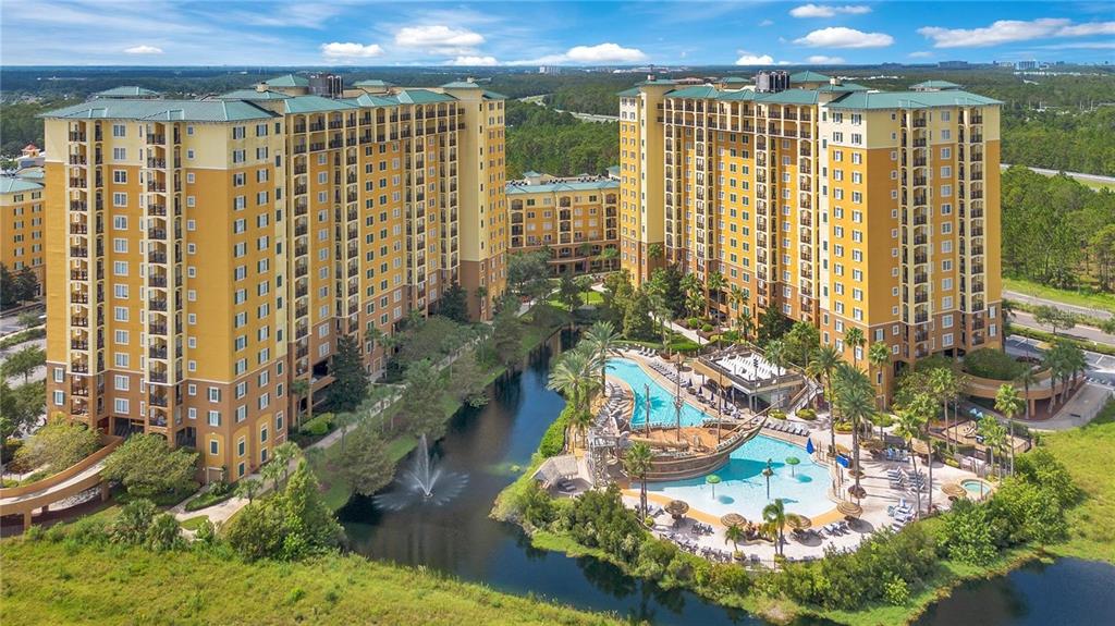 An aerial view shows two large yellow apartment buildings beside a pool and a pond — 8101 RESORT VILLAGE DRIVE UNIT 3905, ORLANDO, FL