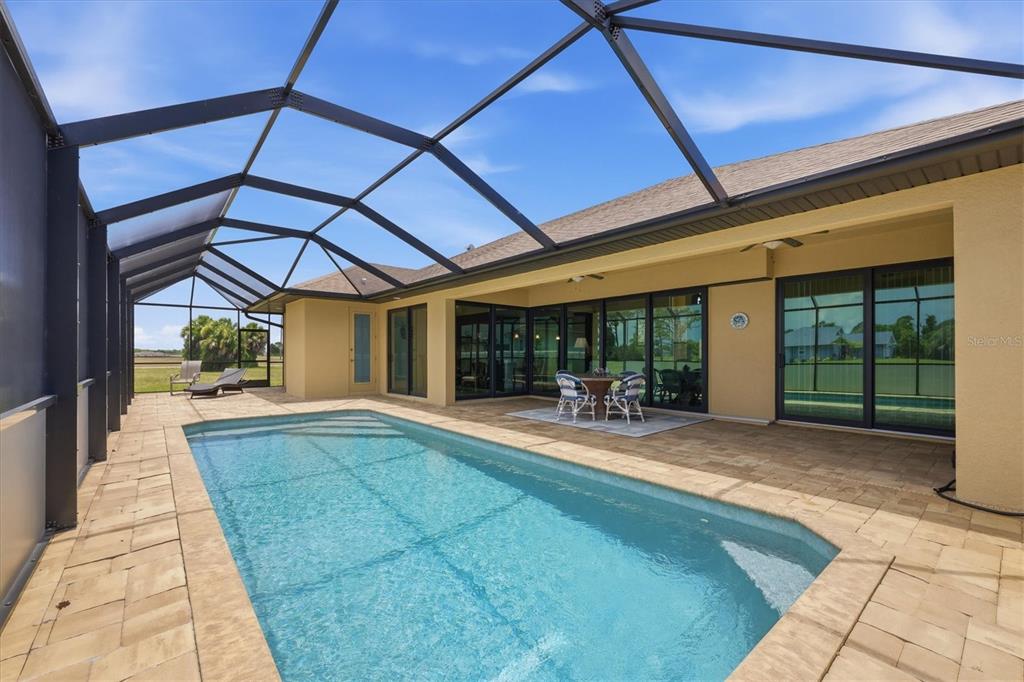 A swimming pool sits on a paved patio enclosed by a large screened-in lanai — 60 HARNESS ROAD, PLACIDA, FL