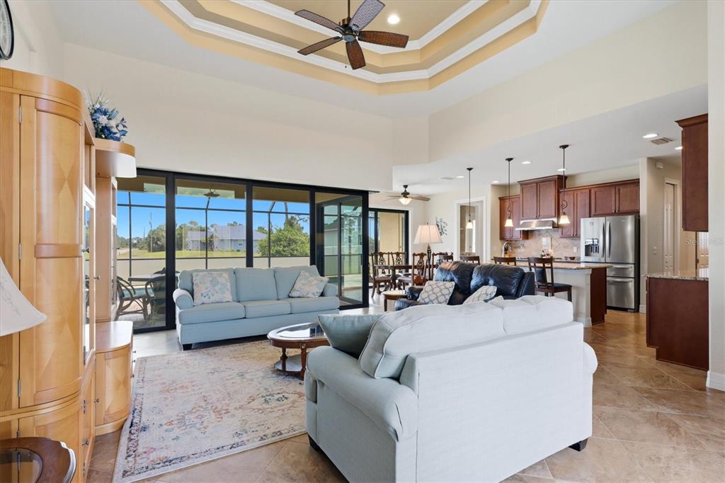 A spacious living room with a tray ceiling opens to a kitchen and a screened patio — 60 HARNESS ROAD, PLACIDA, FL