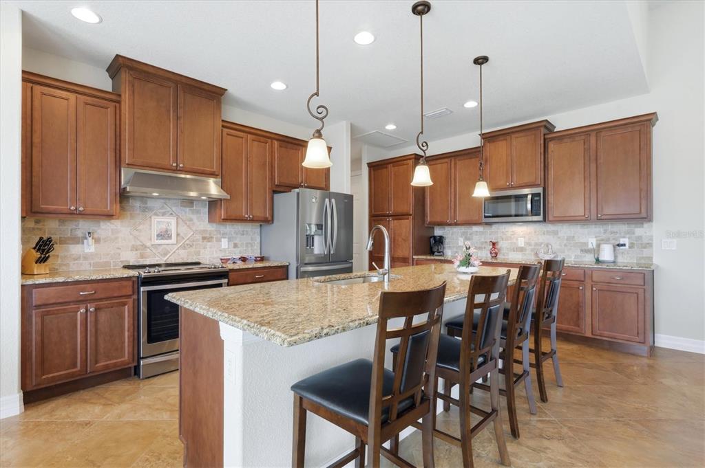 A kitchen features wood cabinets, granite countertops, a center island with seating, and tile flooring — 60 HARNESS ROAD, PLACIDA, FL
