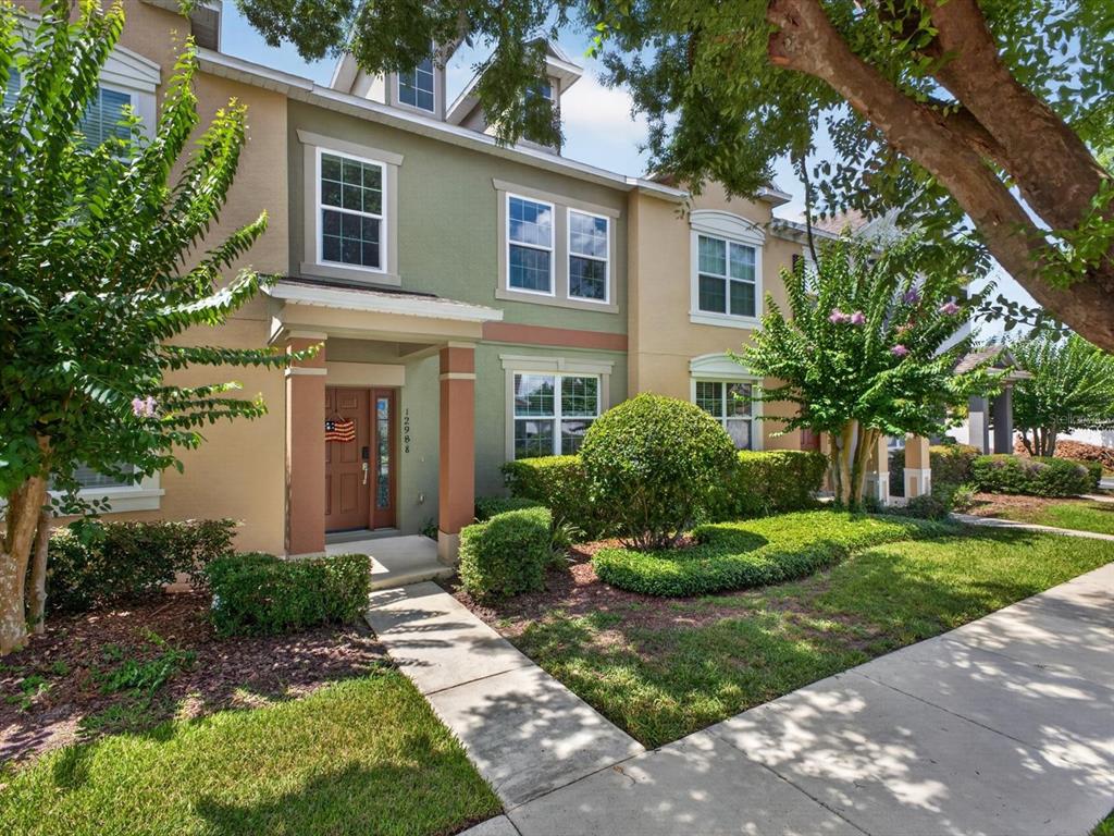 A two-story townhouse exterior features a green and tan facade with a covered front entrance — 12988 BORLAND STREET, WINDERMERE, FL