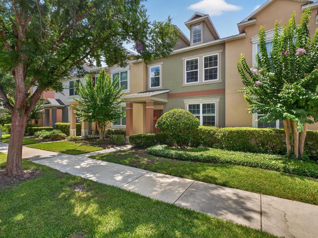A multi-story townhouse exterior with a green and tan facade, sidewalk, and landscaped front yard — 12988 BORLAND STREET, WINDERMERE, FL