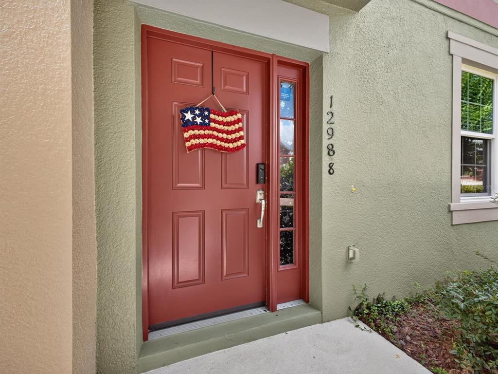 A red front door with an American flag wreath and house numbers on the side — 12988 BORLAND STREET, WINDERMERE, FL