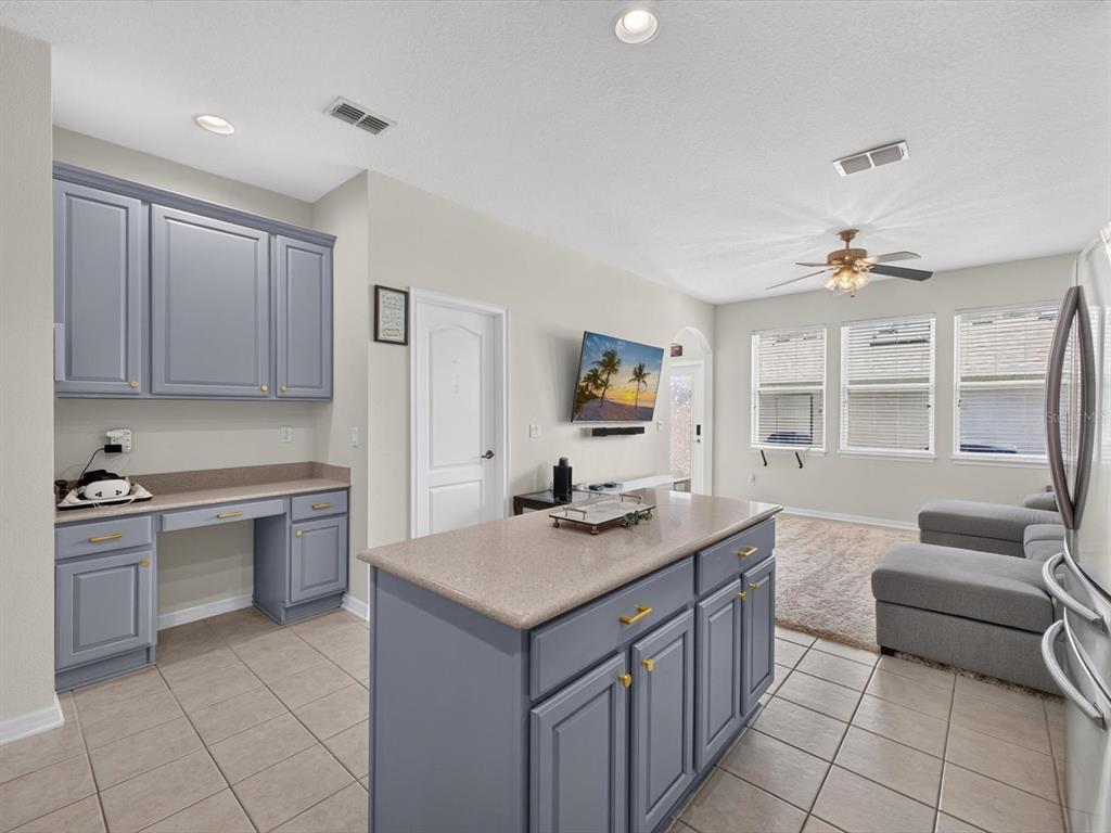A kitchen features blue cabinets, a central island with a countertop, and an adjacent living area — 12988 BORLAND STREET, WINDERMERE, FL