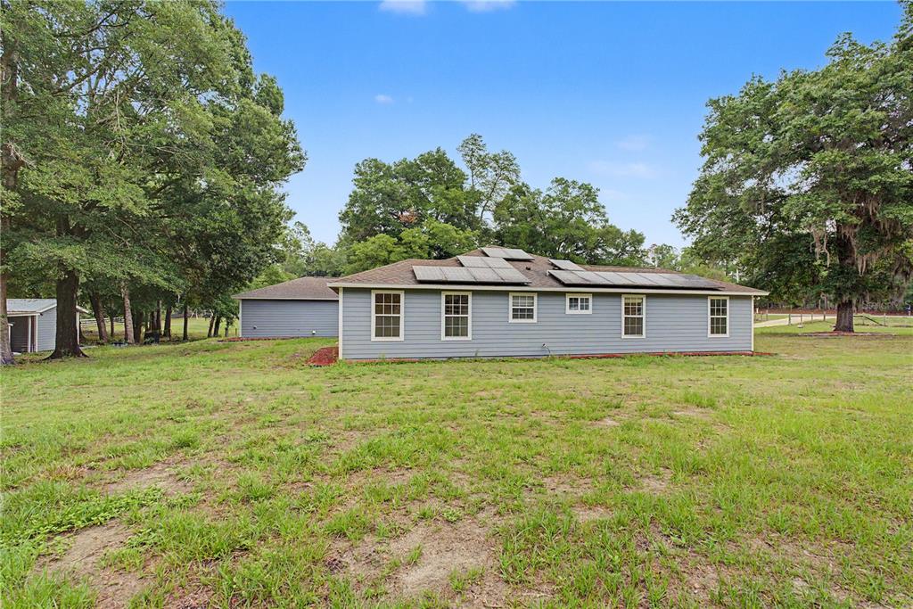 A single-story house with gray siding and solar panels on the roof sits on a lawn — 5160 NE COUNTY ROAD 340, HIGH SPRINGS, FL