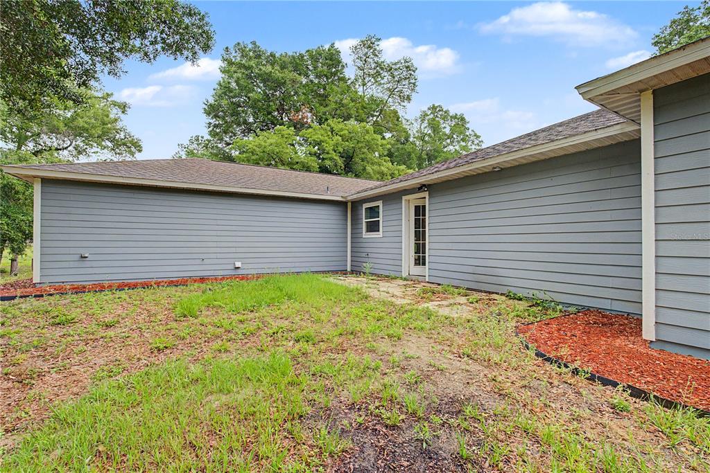 The exterior of a gray, single-story house features a small patio and a grassy yard — 5160 NE COUNTY ROAD 340, HIGH SPRINGS, FL