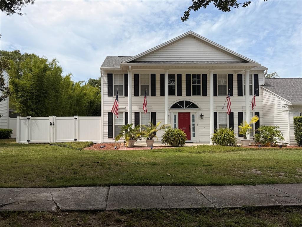 A two-story white house with a red front door and four American flags — 2142 COUNTRY SIDE DRIVE, APOPKA, FL