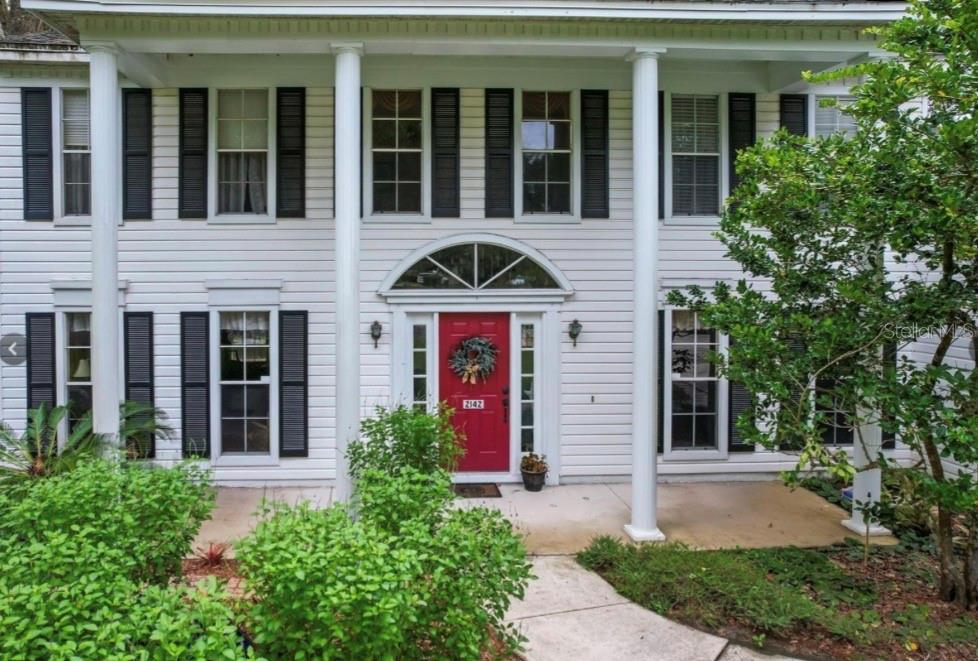 A two-story white house with a red front door and four large front columns — 2142 COUNTRY SIDE DRIVE, APOPKA, FL