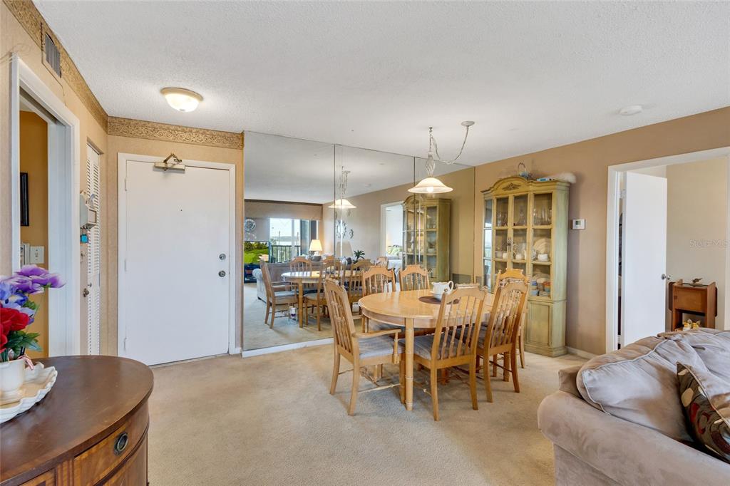 A dining area features a round wooden table, chairs, and a large mirrored wall — 19029 US HIGHWAY 19 N UNIT 9-308, CLEARWATER, FL
