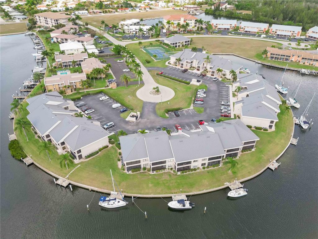 An aerial view shows a waterfront condominium complex with a circular driveway and boat slips — 3256 WHITE IBIS COURT UNIT 324, PUNTA GORDA, FL