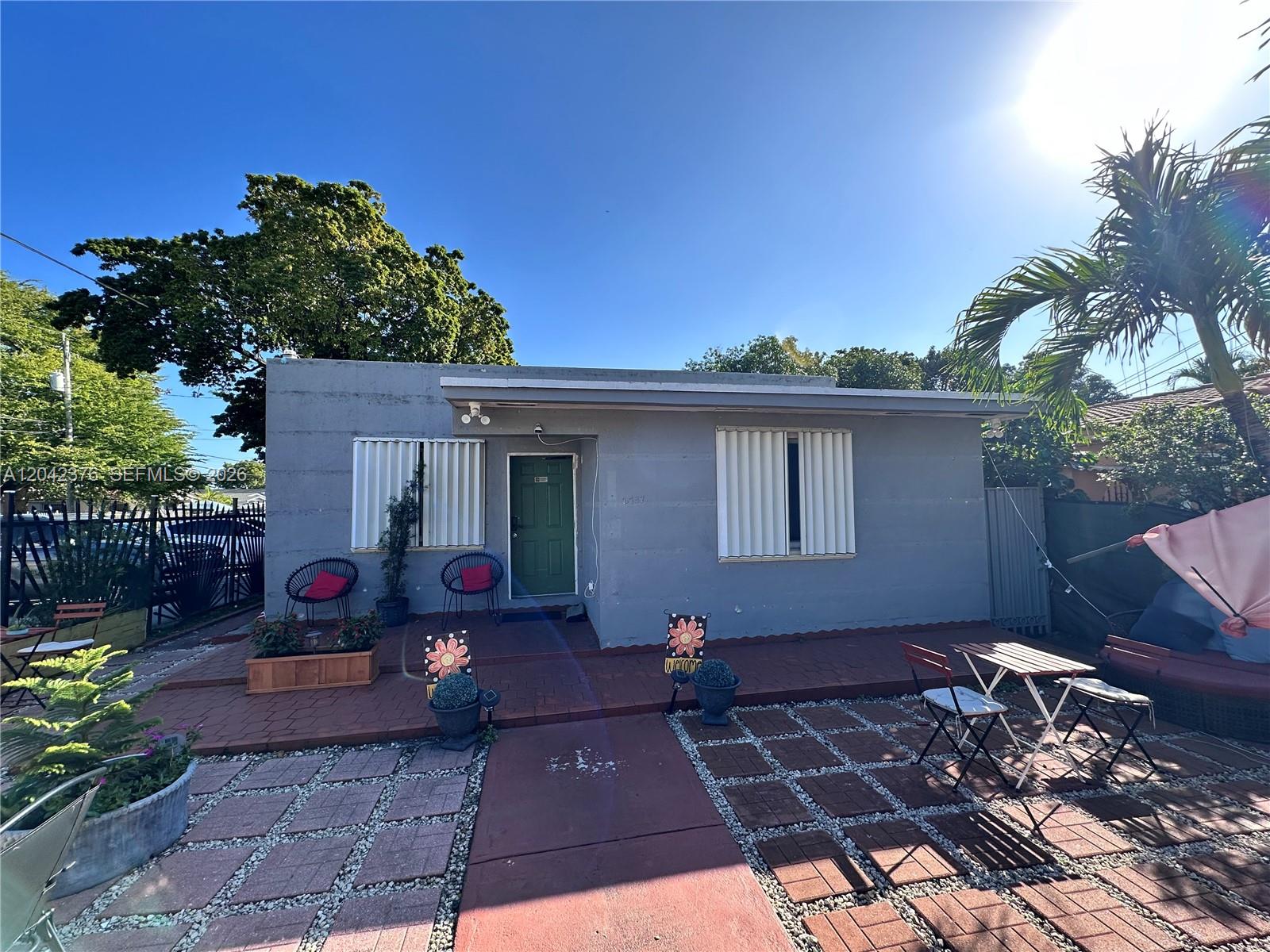 A single-story gray house features a green front door, white shutters, and a paved patio — 2737 NW 13th Ave, Miami FL 33142, MIAMI, FL