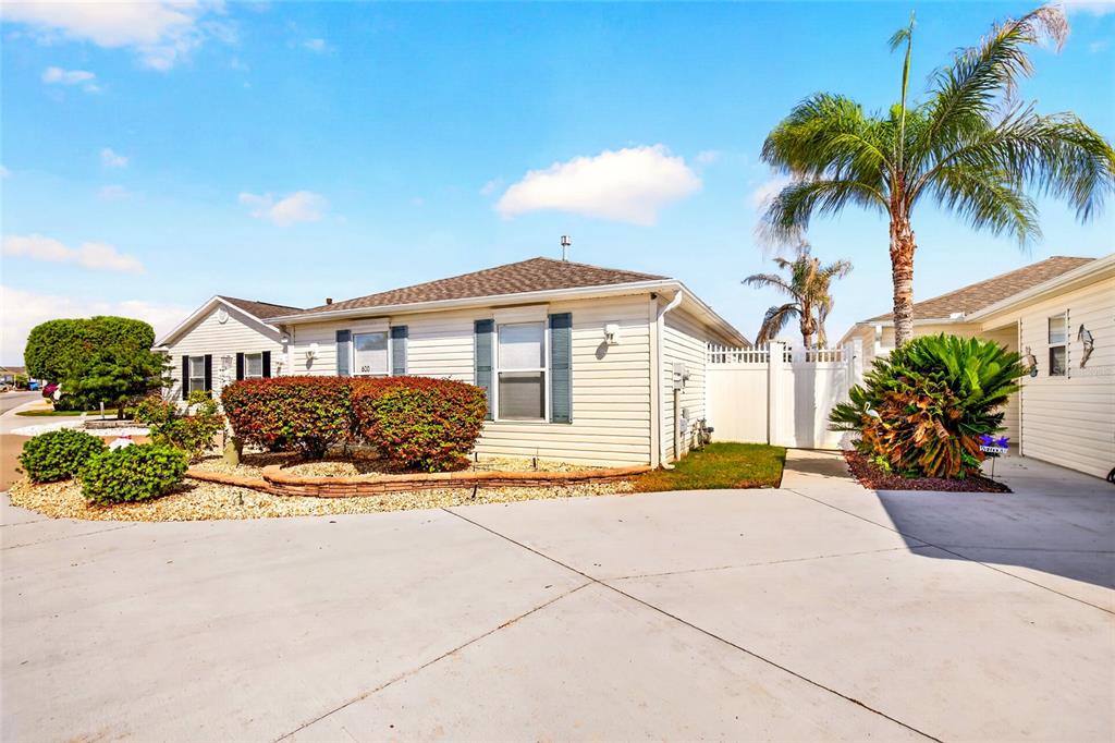 A light-colored single-story house with a concrete driveway, landscaping, and a palm tree — 600 AUDREY LANE, THE VILLAGES, FL