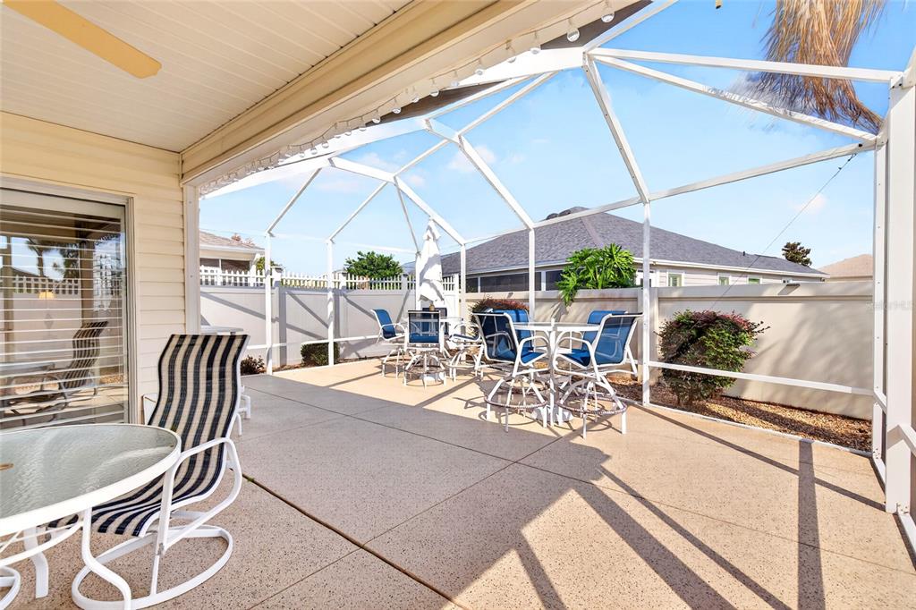 A screened-in patio features a concrete floor, outdoor furniture, and a view of neighboring houses — 600 AUDREY LANE, THE VILLAGES, FL