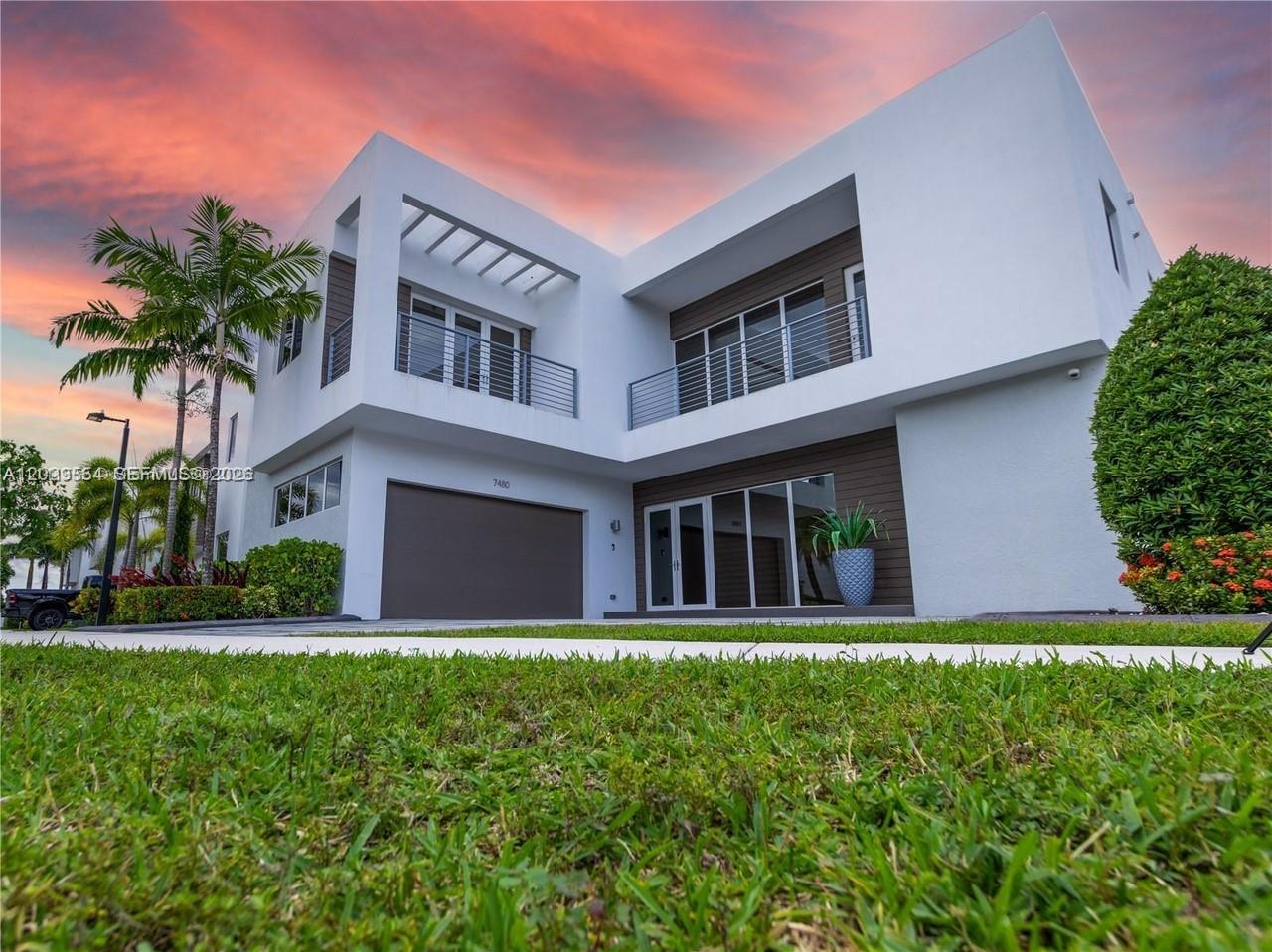 A modern two-story white house with a garage and balconies under a sunset sky — 7480 NW 99th Ave, Doral FL 33178, DORAL, FL